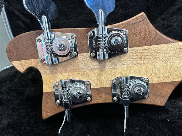 Close-up of chrome Rickenbacker tuning pegs on the back of a two-tone wooden guitar headstock in a black guitar case interior