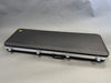 Black hard shell rectangular guitar case with silver latches and handle on gray background