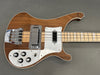 Electric bass guitar with natural wood finish, chrome bridge and pickups, white pickguard, and black control knobs on gray background.