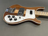Natural wood finish electric bass guitar with white pickguard, chrome bridge, four control knobs, and maple neck on gray background