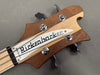 Close-up of Rickenbacker bass guitar headstock with wooden finish and chrome tuning pegs on gray surface