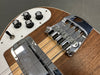 Close-up of electric guitar body showing chrome bridge, four control knobs for bass, treble, and tone, and a toggle switch on natural wood finish background