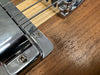 Close-up of chrome bridge and metal strings on natural wood finish electric guitar body at Coffee House Guitars