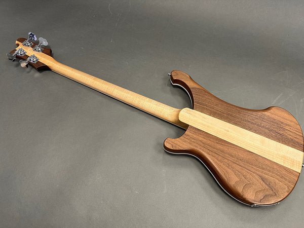 Back view of electric bass guitar with natural wood finish and maple stripe running down the center, showcasing neck and tuning pegs.