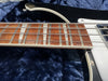 Close-up of four-string electric bass guitar fretboard with metal frets and wound strings on dark blue plush surface