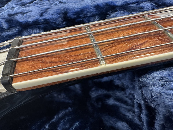 Close-up of guitar fretboard with steel strings and metal frets on a dark blue plush background