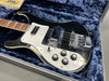 Black and white electric bass guitar with chrome hardware and four control knobs in plush blue hard case