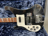 Black electric bass guitar with white pickguard and chrome bridge hardware resting in blue plush-lined guitar case