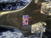Close-up of black guitar headstock with chrome tuning machines and a "Made in America" sticker on a blue fabric background