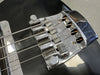 Close-up of black electric bass guitar bridge and strings showing chrome hardware and saddles