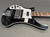 Black electric bass guitar with white pickguard, chrome hardware, and rosewood fretboard on gray background
