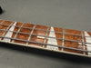 Close-up of electric bass guitar fretboard with pearl inlays and silver frets on dark background
