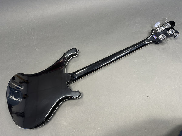 Black electric bass guitar back view showing body, neck, and headstock with tuning pegs on gray background