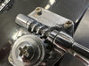Close-up of chrome Rickenbacker tuning machine on black electric guitar headstock with visible gear and Phillips screws