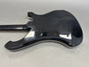 Back view of black electric guitar body with white binding on gray surface
