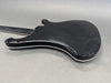Back side of black electric guitar body with cream binding on a gray background