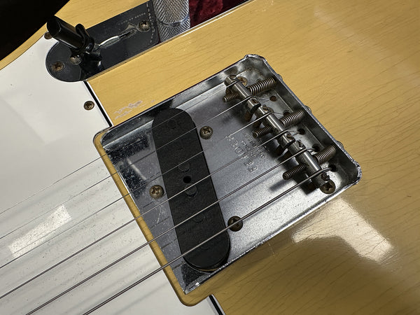 Close-up of vintage electric guitar bridge and single-coil pickup with metal saddles and screws on butterscotch finish body at Coffee House Guitars