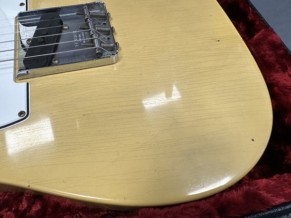 Close-up of relic vintage cream electric guitar body with single coil pickup and aged finish in red plush-lined guitar case