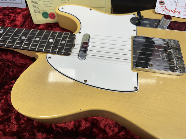 Close-up of vintage Fender Telecaster guitar body in butterscotch blonde finish with white pickguard and black rosewood fretboard on red velvet background