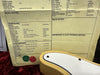 Close-up of guitar specification sheet showing hardware and electronics details for a Nocaster Blonde 1967 Telecaster reissue with 67 Tele Rel bridge and 60 Tele P/B/P Nitro Rel pickguard next to the body of a blonde electric guitar with white pickguard on red plush background