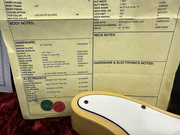Close-up of guitar specification sheet showing hardware and electronics details for a Nocaster Blonde 1967 Telecaster reissue with 67 Tele Rel bridge and 60 Tele P/B/P Nitro Rel pickguard next to the body of a blonde electric guitar with white pickguard on red plush background