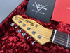Close-up of Fender Telecaster headstock with chrome tuning pegs on red plush guitar case lining and Fender Custom Care booklet