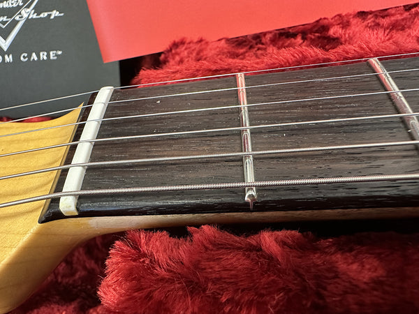 Close-up of Fender guitar nut and first fret on maple neck with rosewood fretboard and steel strings in red plush case