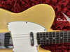 Close-up of vintage yellow electric guitar body and fretboard with white pickguard on red plush case background
