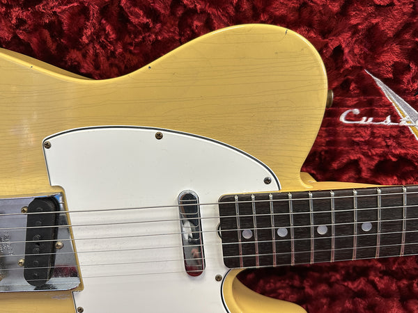Close-up of vintage yellow electric guitar body and fretboard with white pickguard on red plush case background