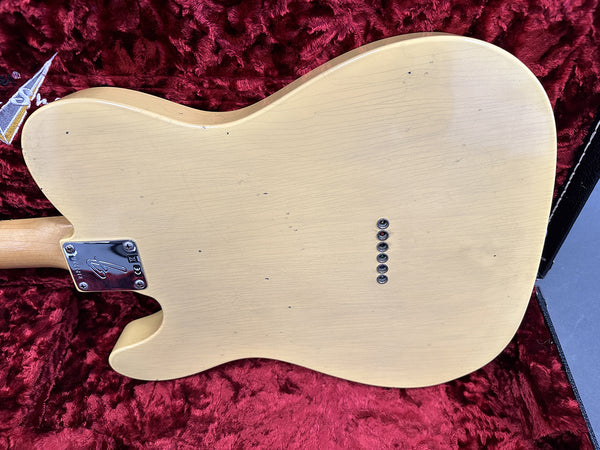 Vintage cream electric guitar body back showing string ferrules and chrome neck plate with Fender logo on red plush guitar case interior