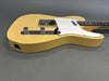 Vintage yellow electric guitar body with white pickguard and chrome control knobs on gray background