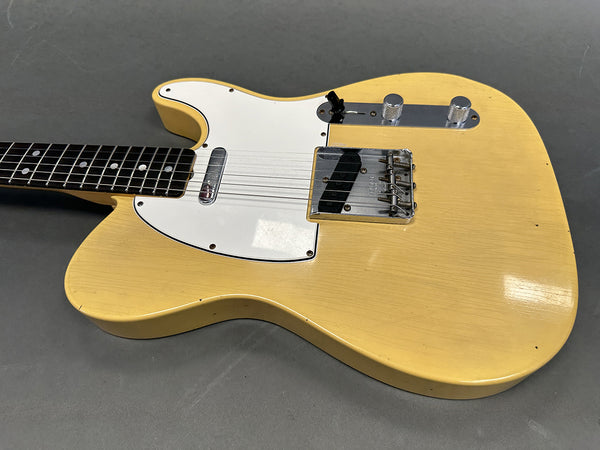 Vintage yellow solid body electric guitar with white pickguard, chrome bridge, and black rosewood fretboard on gray background