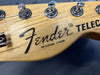 Close-up of Fender Telecaster guitar headstock with tuning pegs and strings on natural wood finish