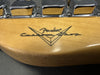 Close-up of Fender Custom Shop logo on natural wood guitar neck with chrome tuning pegs