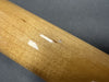 Close-up of guitar neck wood finish with small chip and dent damage on a light brown maple neck against a gray background