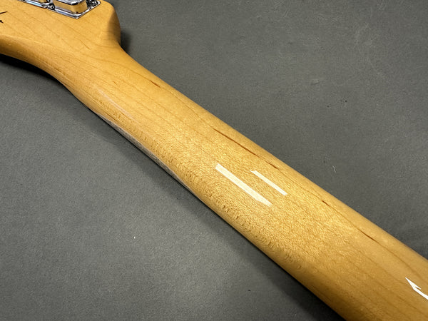 Close-up of maple guitar neck with smooth finish and tuning pegs on gray background