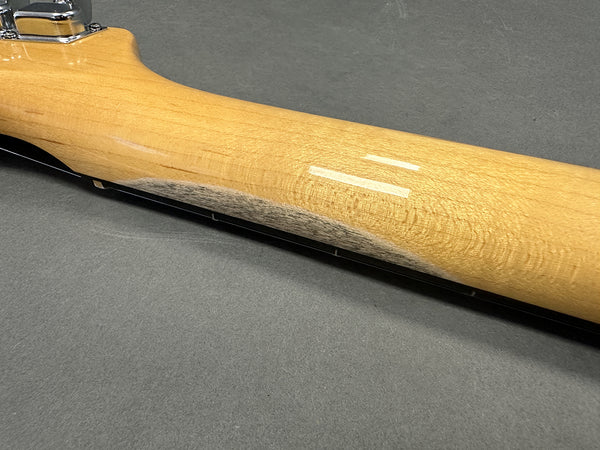 Close-up of maple guitar neck showing smooth finish and subtle wood grain detail on gray background