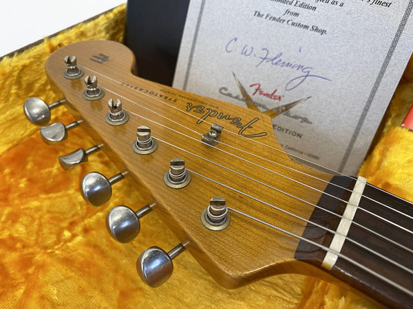 Close-up of Fender Stratocaster guitar headstock with tuning pegs and certificate in yellow plush-lined case