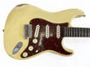 Vintage cream electric guitar with tortoiseshell pickguard and three single-coil pickups, showing aging and wear.