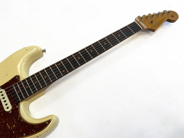 Vintage Fender Stratocaster electric guitar neck and partial body with worn cream finish and tortoiseshell pickguard on white background