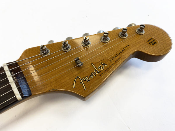 Close-up of a vintage Fender Stratocaster guitar headstock with tuning pegs, natural wood finish, and original contour badge on a white background.
