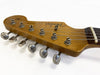Close-up of vintage Fender Stratocaster guitar headstock with tuning pegs and strings on white background