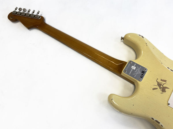 Back view of vintage cream Fender Stratocaster electric guitar with maple neck and tuning pegs, showing aging and wear marks on body and neck plate with serial number and Fender logo.