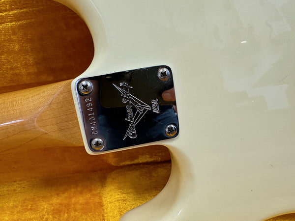 Close-up of guitar neck plate with Custom Shop USA engraving and serial number CWA01492 on cream electric guitar body