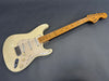 Vintage cream Fender Stratocaster electric guitar with maple neck and three single-coil pickups on gray background