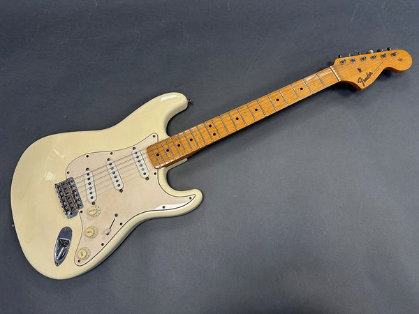 Vintage cream Fender Stratocaster electric guitar with maple neck and three single-coil pickups on gray background