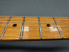 Close-up of guitar maple fretboard with metal frets and six steel strings on dark background