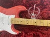 Close-up view of coral red Fender Stratocaster electric guitar neck with maple fretboard and white pickguard on red plush case with embroidered Stratocaster 60 years 1954-2014 logo