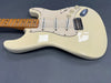 Cream electric guitar with three single-coil pickups and maple neck on gray background