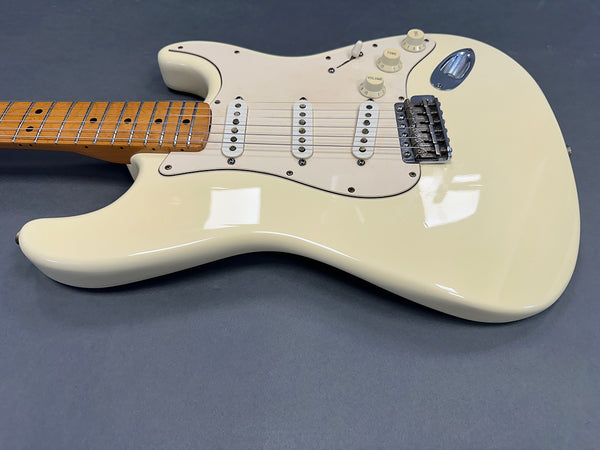 Cream electric guitar with three single-coil pickups and maple neck on gray background